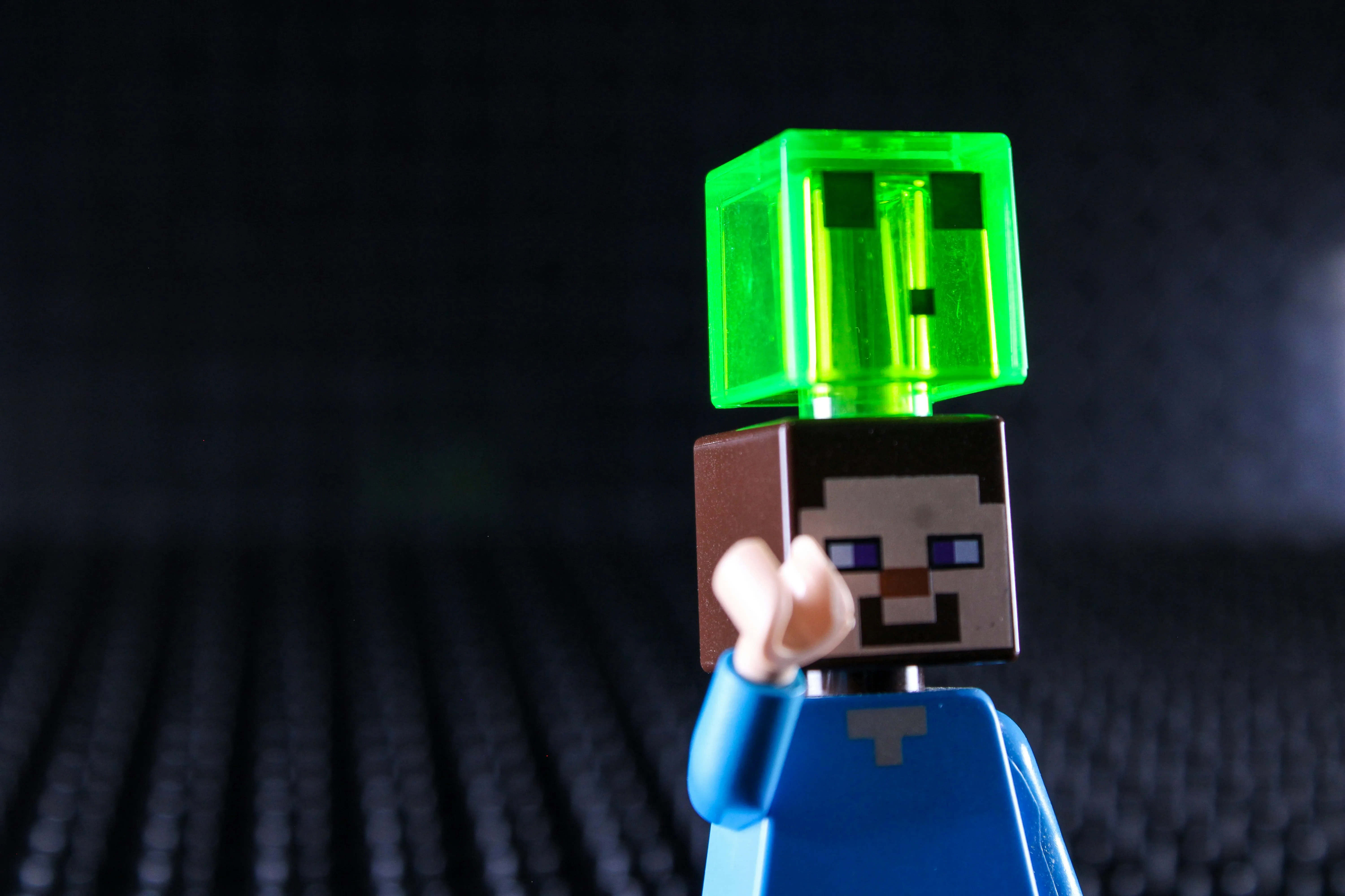 Lego Minecraft figure with a green cube on its head against a dark background