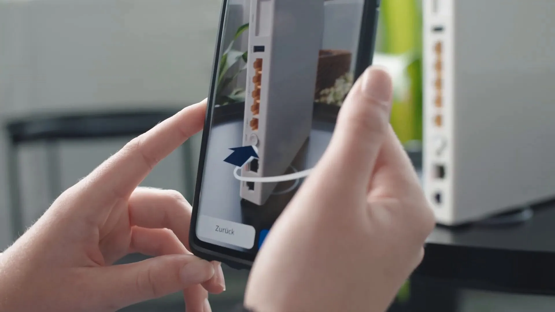 Auf dem Smartphone zeigt ein blauer Pfeil in Augmented Reality, in welche Buchse an der Rückseite des Routers das Kabel gehört