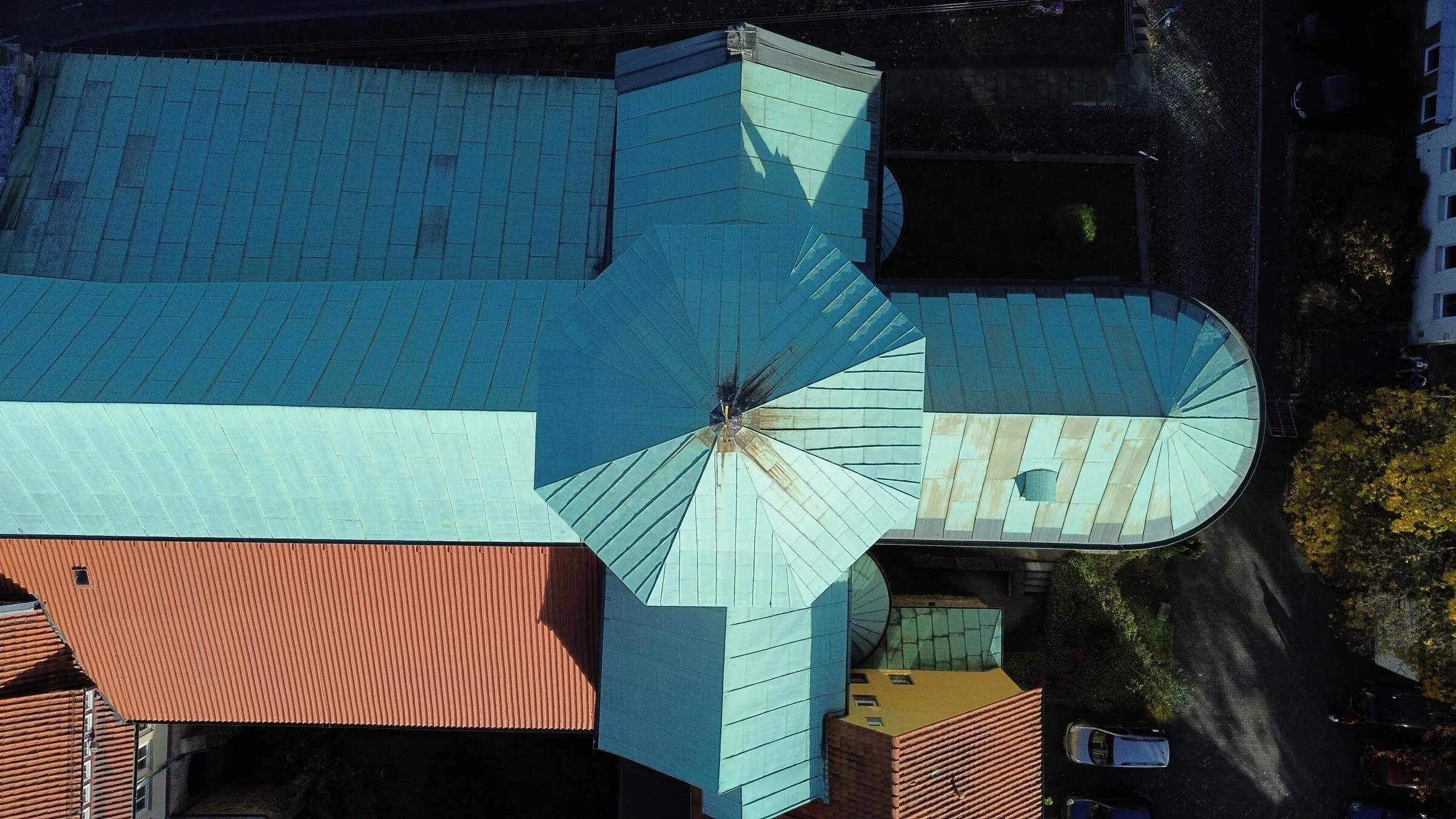 Drohnenaufnahme senkrecht von oben: Das Kupferdach der Kirche Zum Heiligen Kreuz mit Vierungsturm, Querhaus und runder Apsis