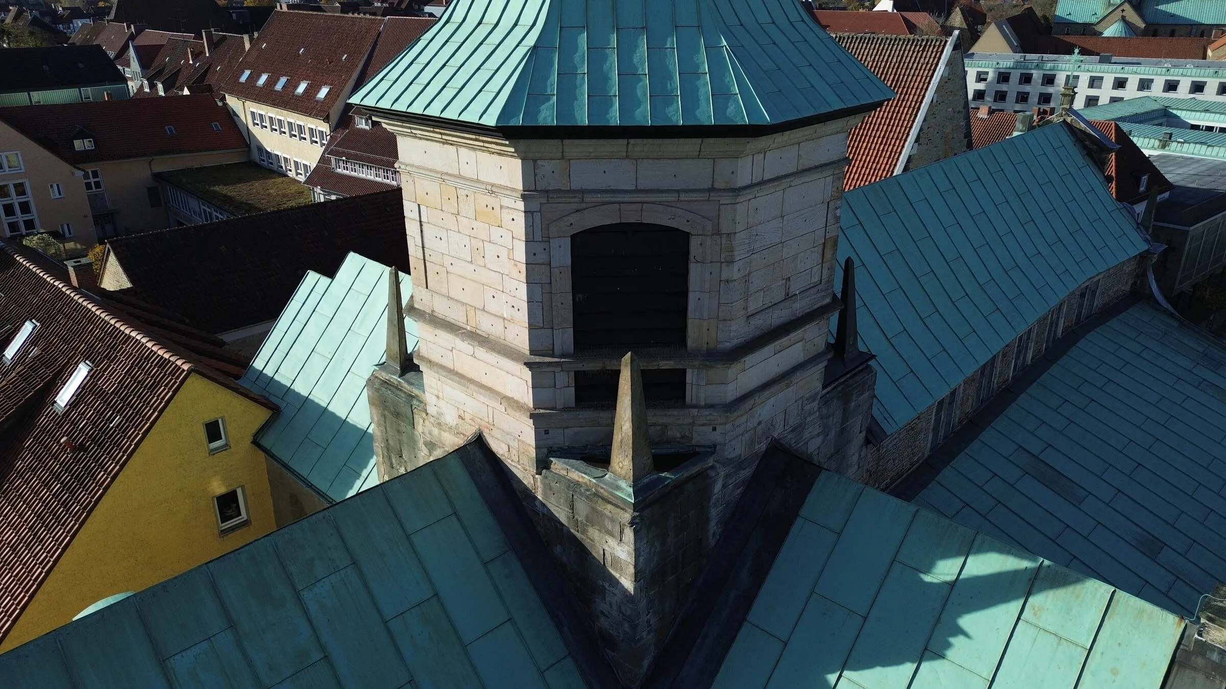 Drohnenaufnahme des Glockenturms der Kirche Zum Heiligen Kreuz mit Schallfenstern und Kupferhaube über den Dächern von Hildesheim