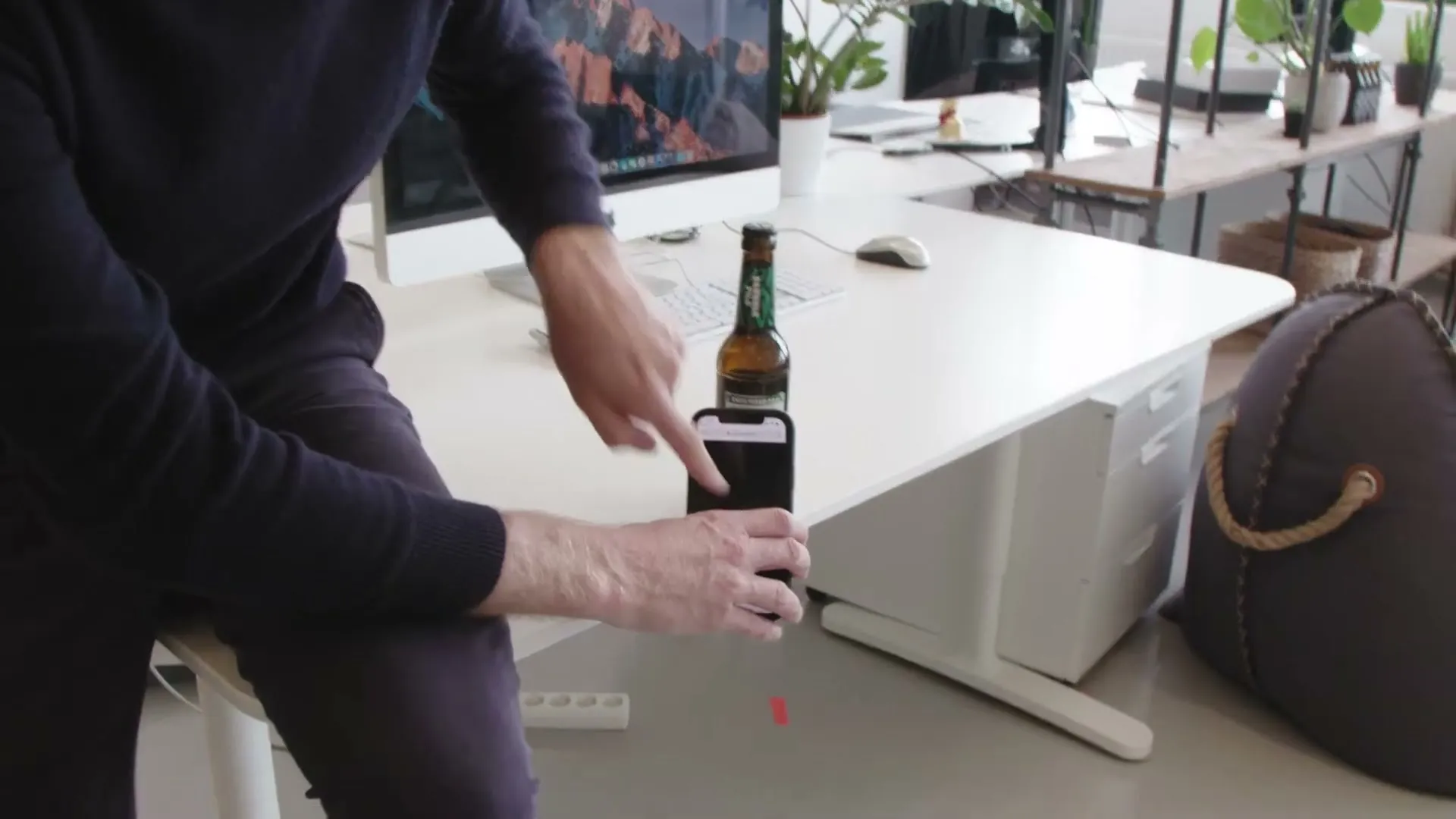 Matthias Wolk von VRtual X hält sein Smartphone an einem Schreibtisch vor das Etikett einer Bierflasche