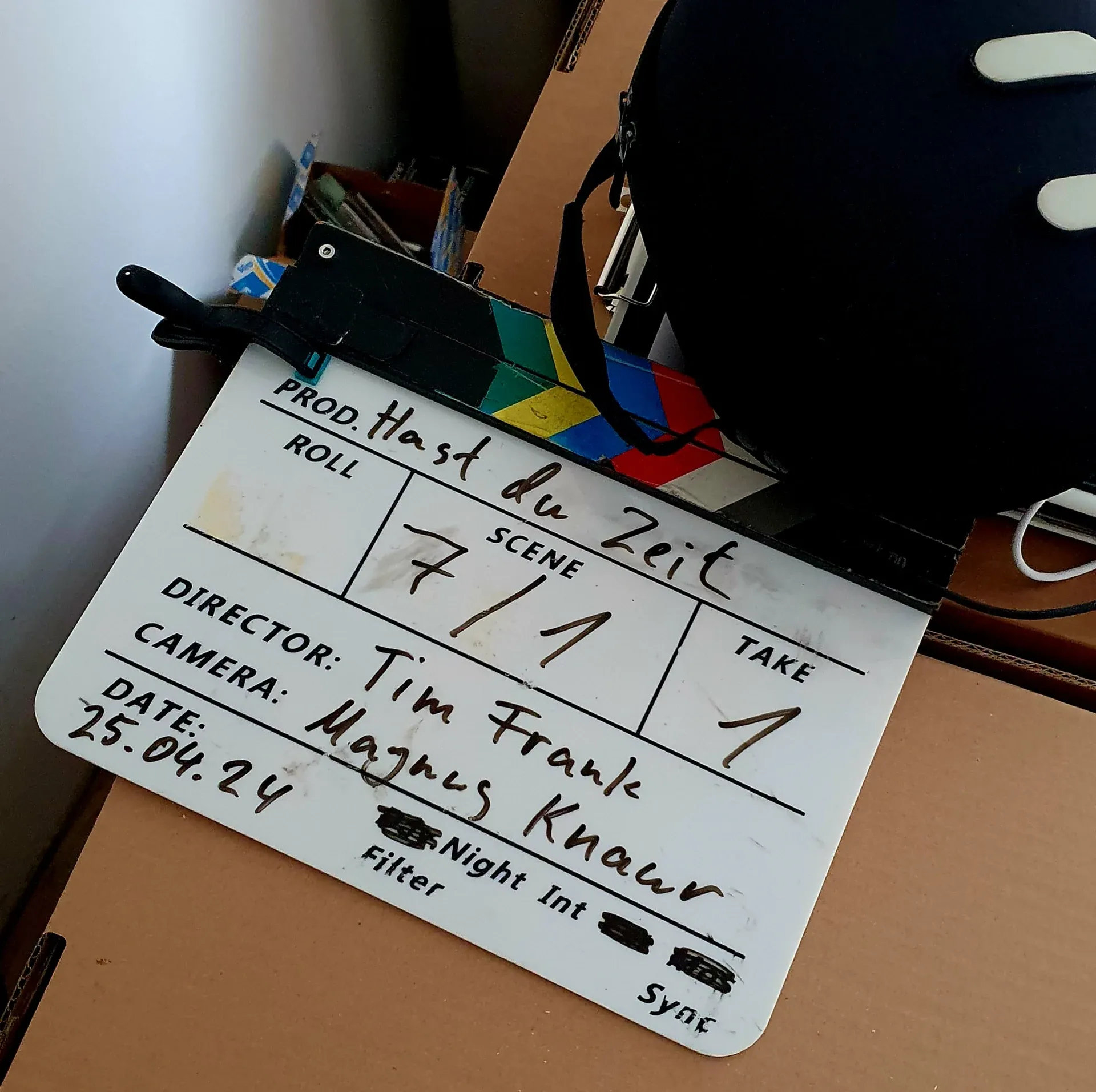 Filmklappe mit der Aufschrift Hast du Zeit, Szene 7/1, Take 1, Datum 25.04.24