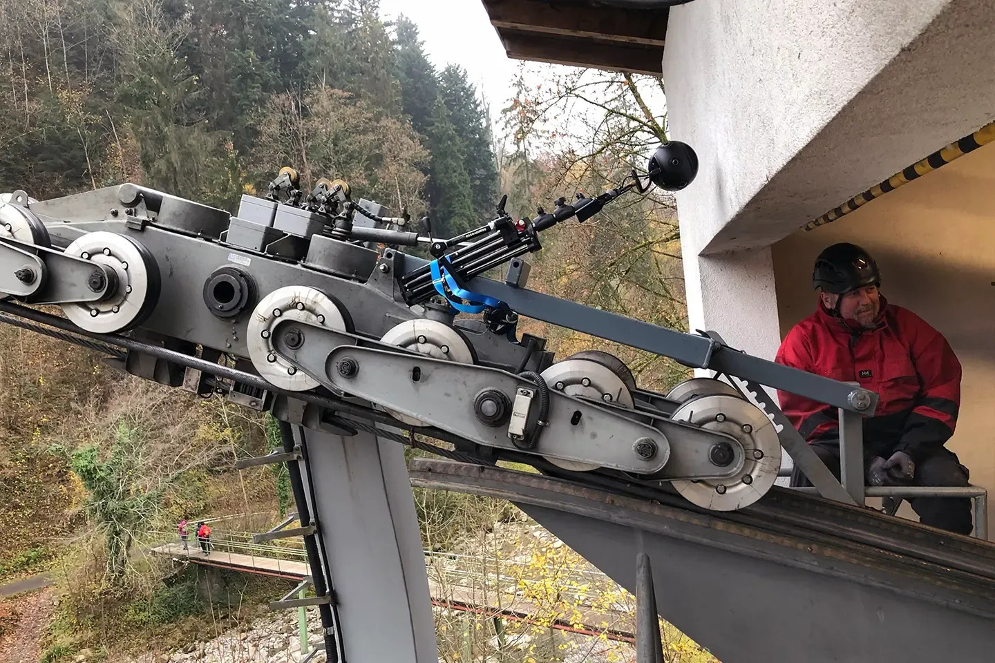 360° camera mounted on a cable car carriage, next to it an inspector wearing a helmet on a platform