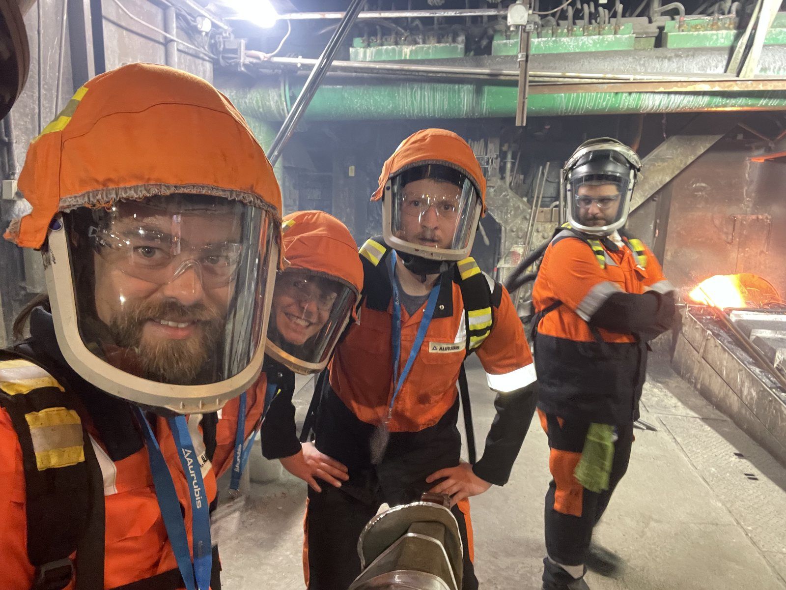 Tim and the team in heat protection suits at the smelting furnace, glowing metal behind them