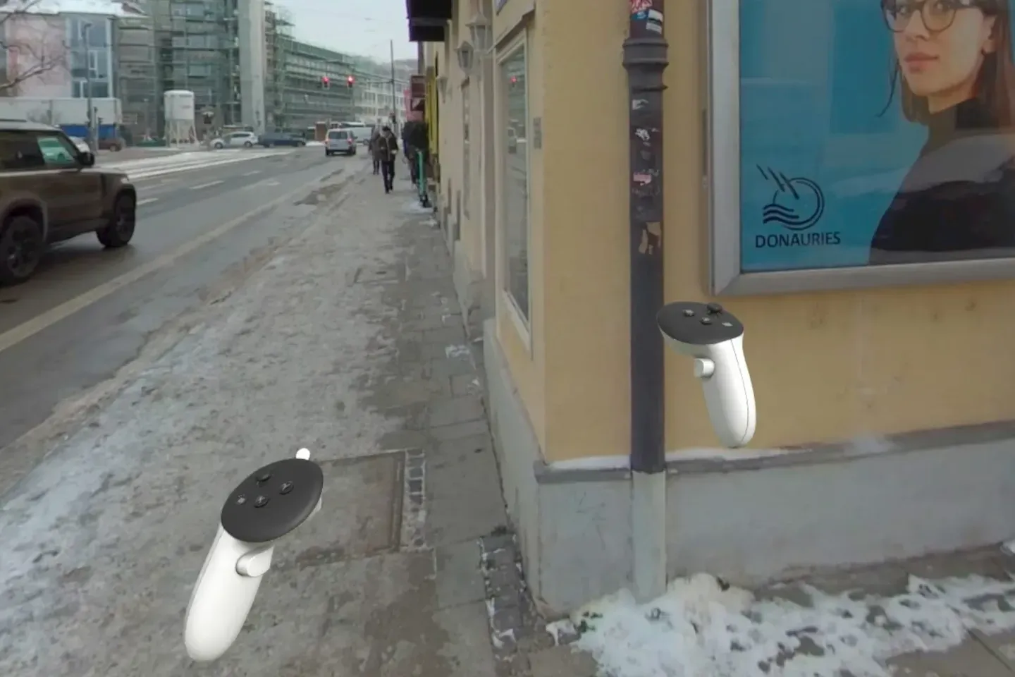 360° view of a snowy Munich street with a billboard on the corner of a building, two VR controllers in the foreground