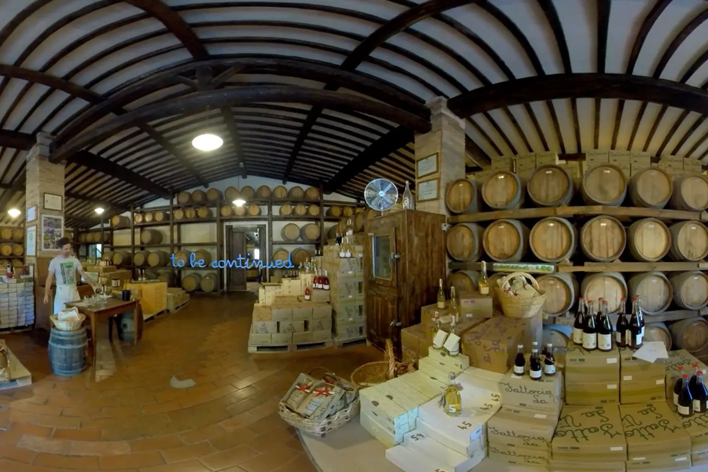 360° shot of the wine cellar with barrels and La Vialla boxes, overlaid with the words “to be continued …”