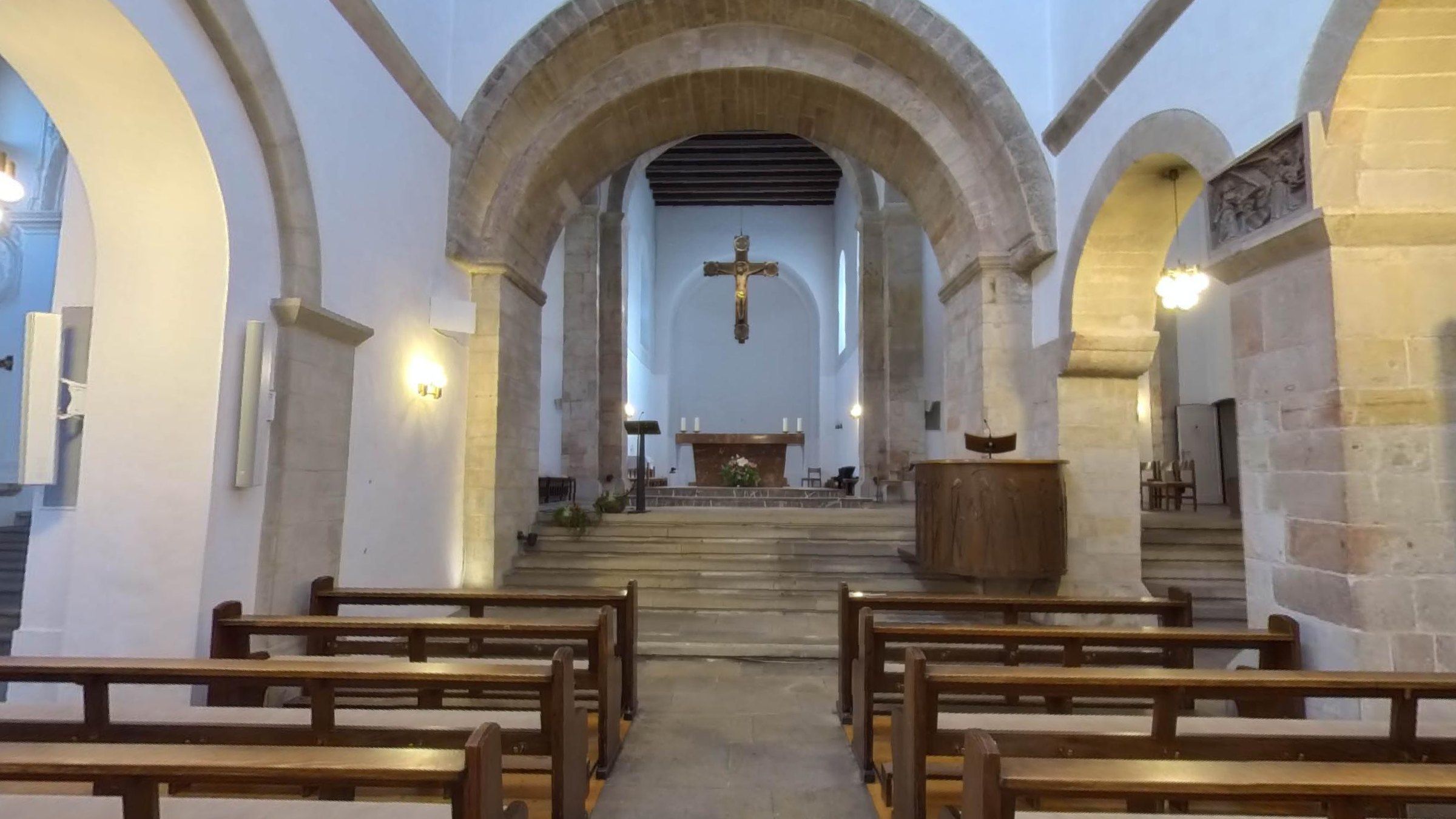 Blick durch das Mittelschiff der Kirche Zum Heiligen Kreuz in Hildesheim auf den romanischen Bogen, den Altarraum und das Kruzifix an der Stirnwand