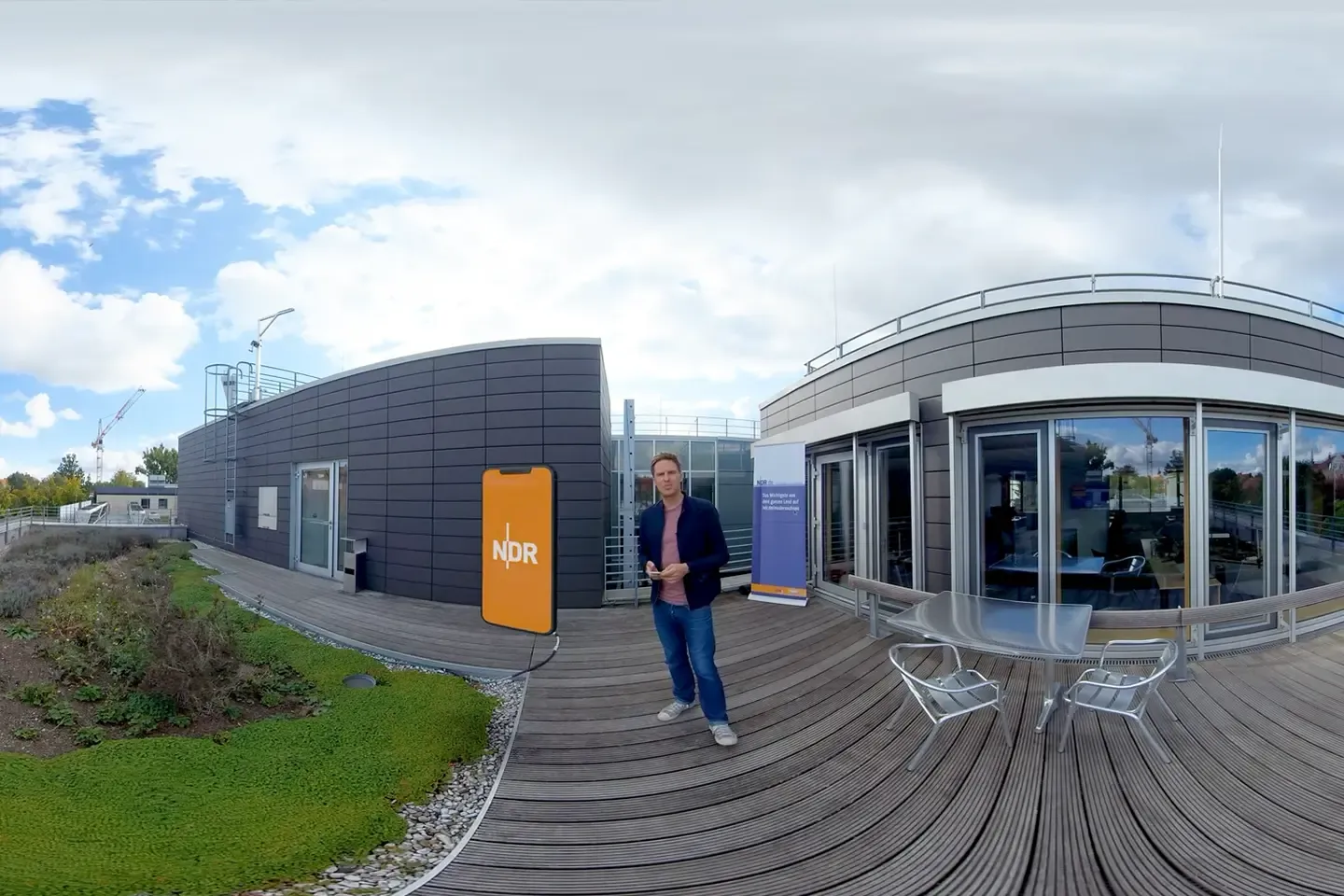 360° shot: the host on a roof terrace next to an overlaid smartphone graphic with the NDR logo