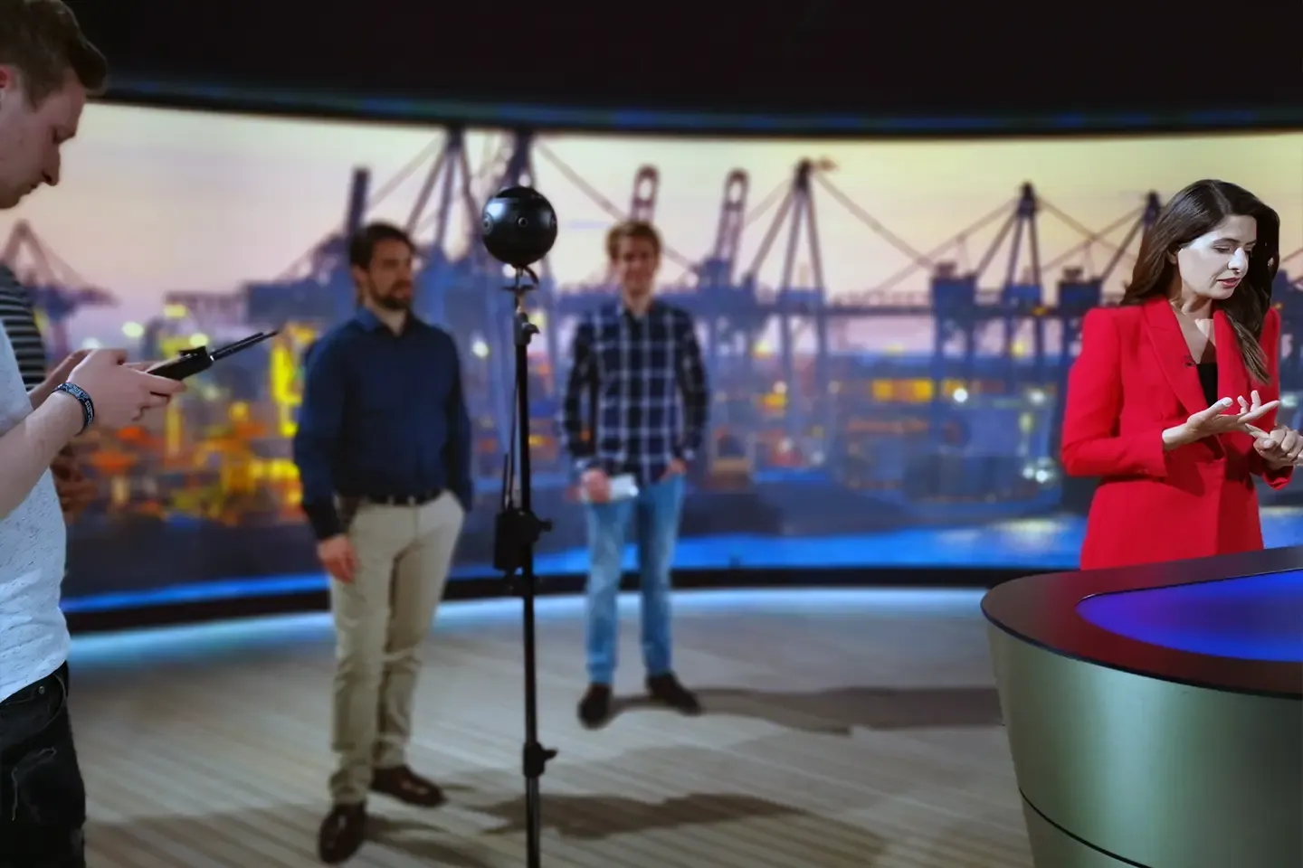 Film crew and Linda Zervakis in the studio in front of a harbor backdrop, the 360° camera on a tripod in the middle