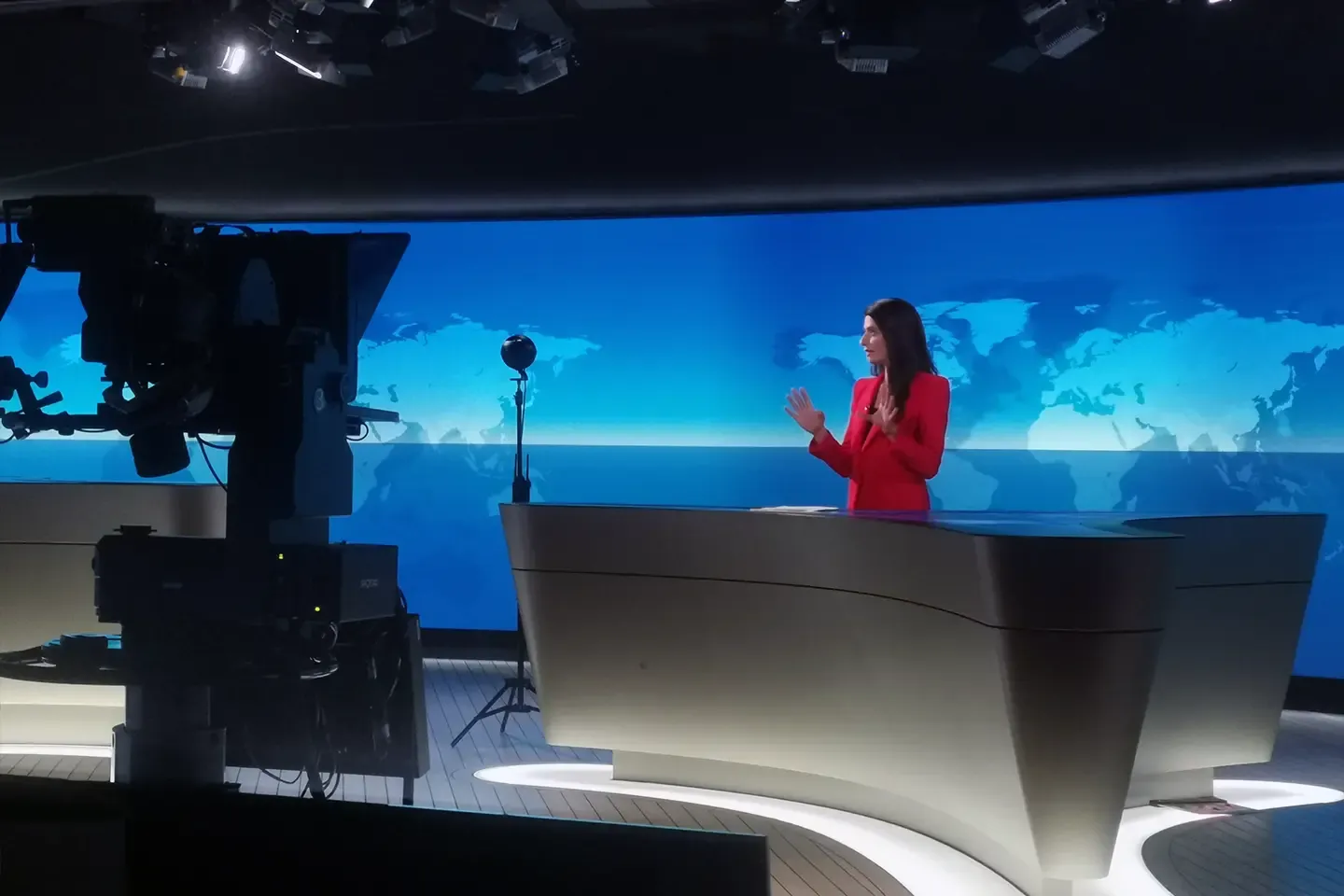 Linda Zervakis at the anchor desk, a studio camera on the left, the 360° camera in front of the blue world map in the background