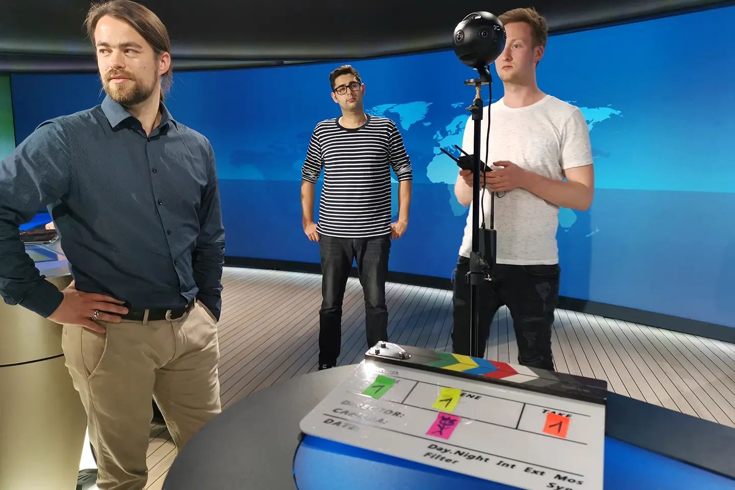 Three members of the film crew with a 360° camera and a clapperboard in the Tagesschau studio