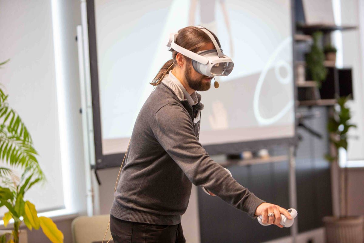 Tim B. Frank stands on stage with a VR headset and gives a talk