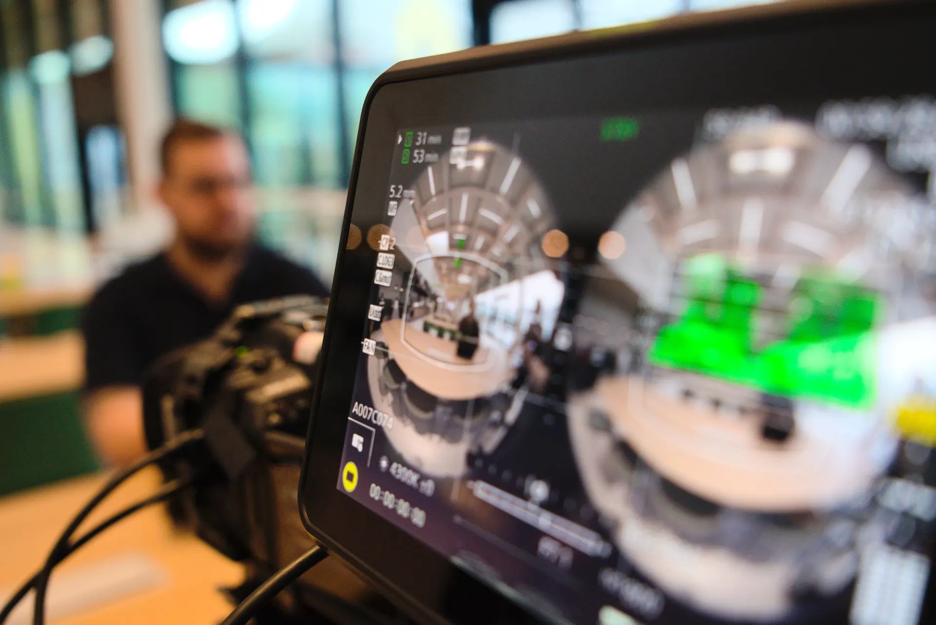 Preview monitor of the 3D camera with two round fisheye images, a blurred man in the background
