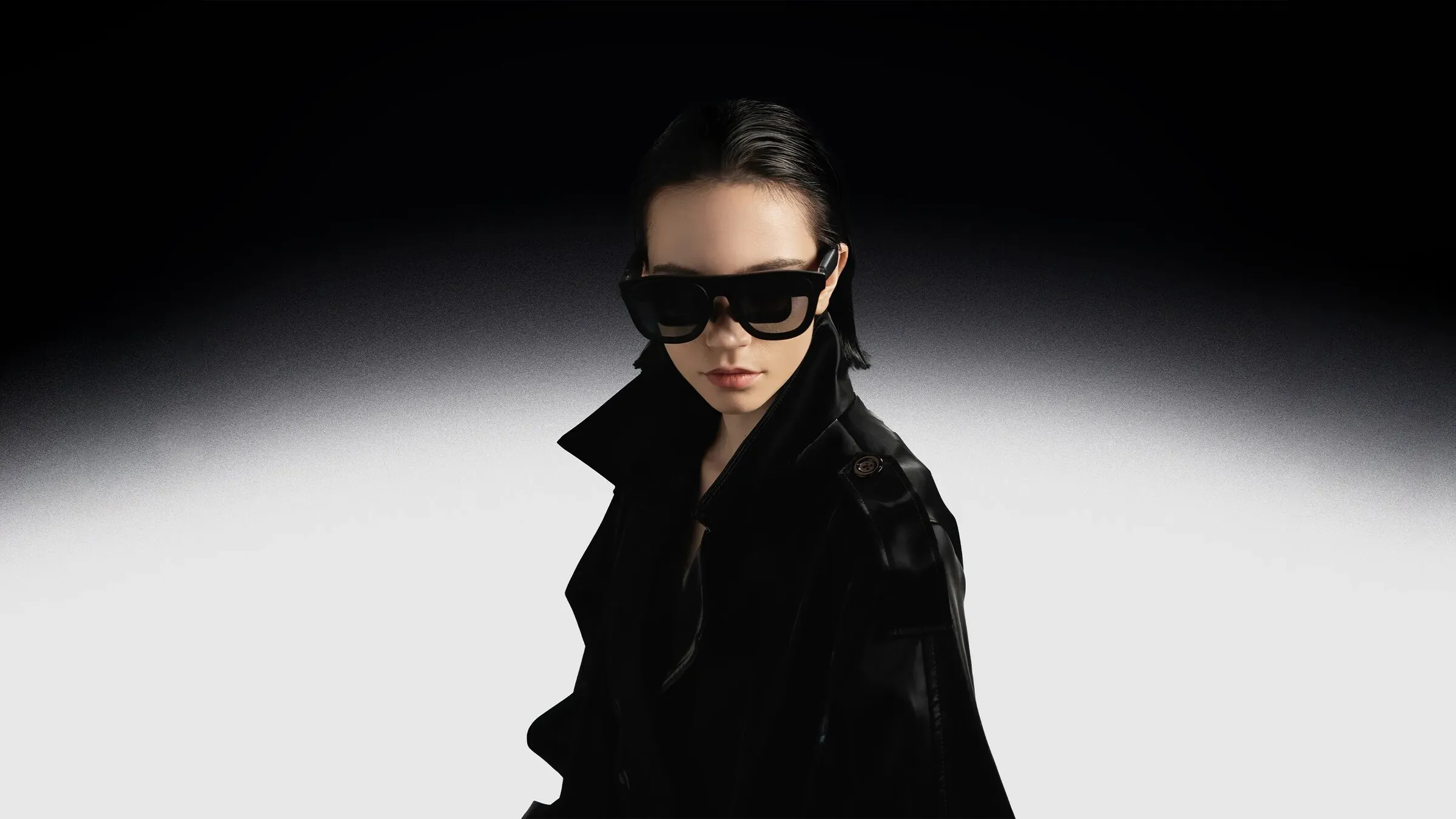 A woman wears the XREAL One Pro, which looks like a pair of dark sunglasses